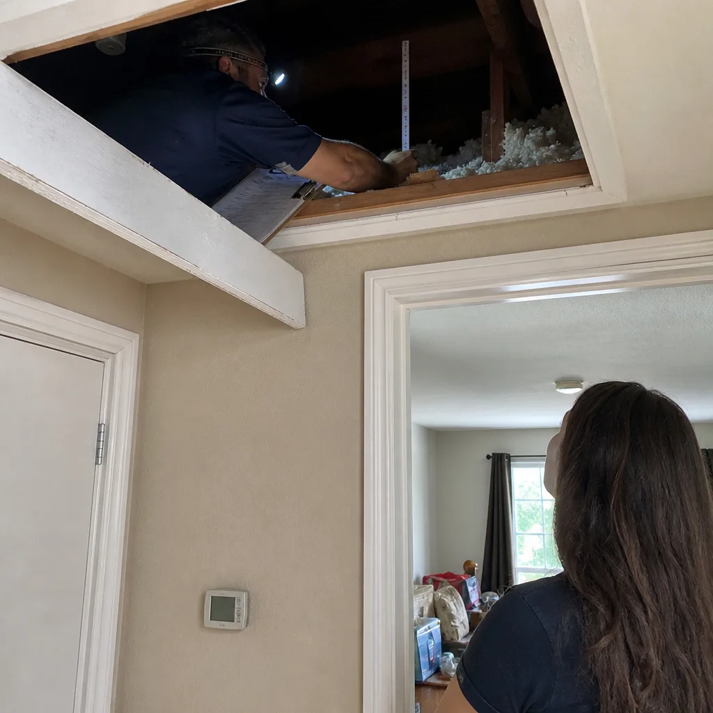 Energy auditor measuring attic insulation depth for a home energy inspection nationwide